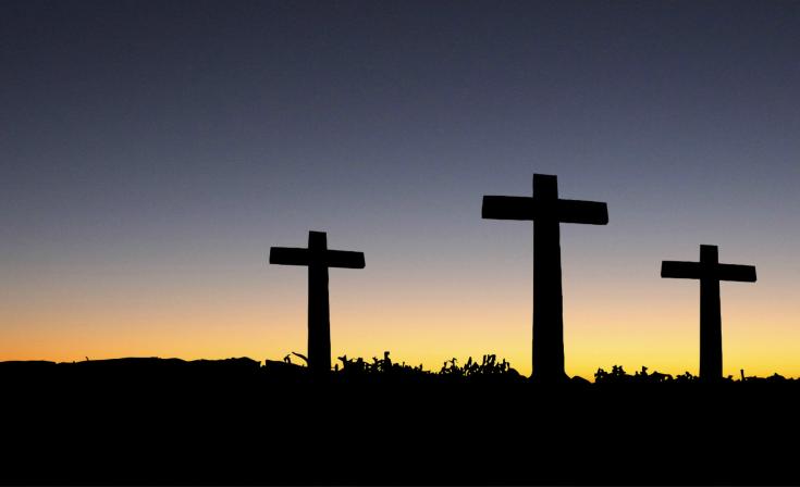 Three crosses silhouetted with a sunset in the background